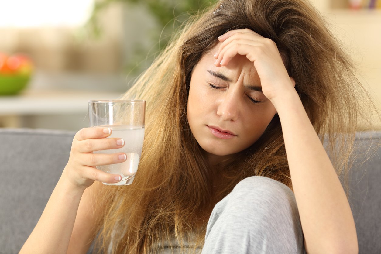 Woman with headache and glass of water